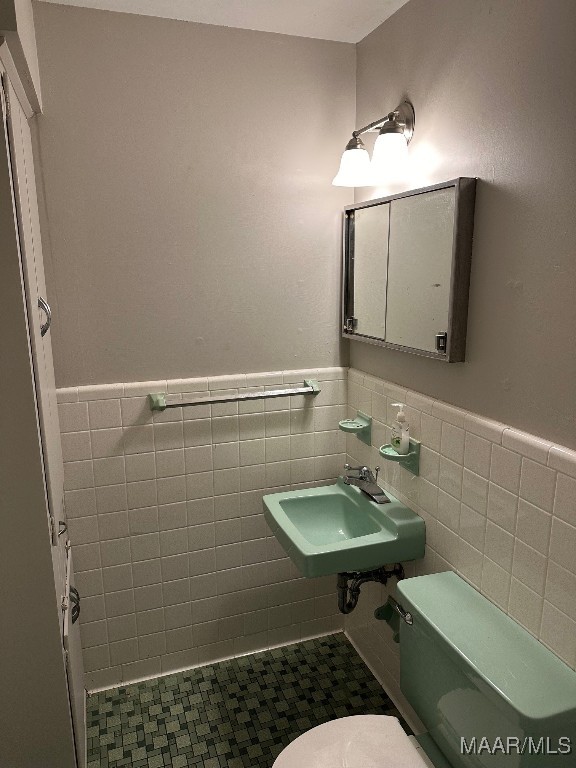 bathroom with tile walls, tile patterned flooring, sink, and toilet