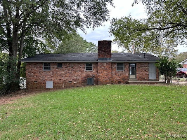 back of house featuring central air condition unit and a lawn