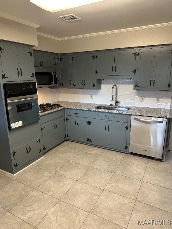 kitchen featuring sink, ornamental molding, backsplash, light stone countertops, and appliances with stainless steel finishes