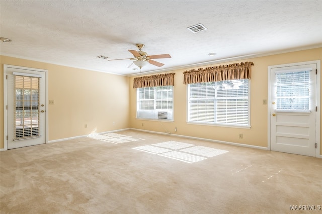 carpeted empty room featuring a textured ceiling, ceiling fan, and crown molding