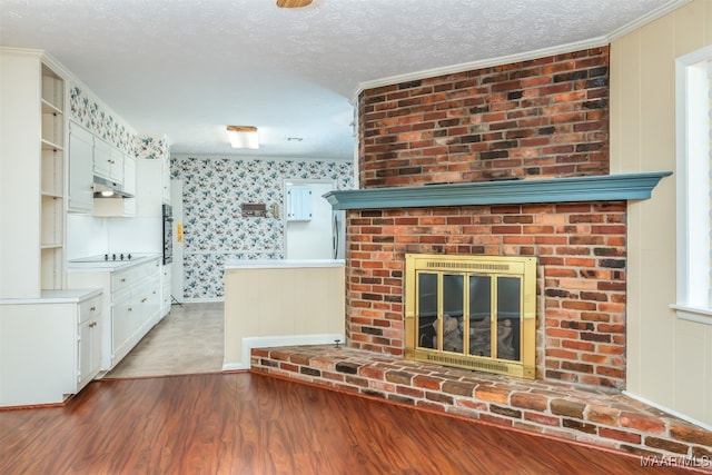 unfurnished living room with a textured ceiling, hardwood / wood-style flooring, ornamental molding, and a fireplace