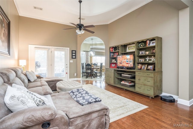 living room with ceiling fan, crown molding, a towering ceiling, and dark wood-type flooring