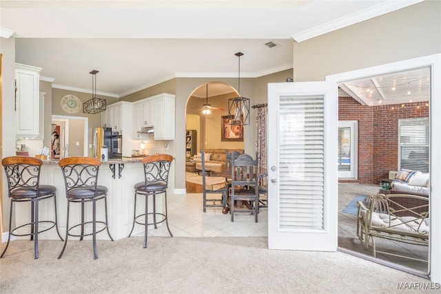 kitchen with a breakfast bar, white cabinets, decorative light fixtures, light colored carpet, and kitchen peninsula