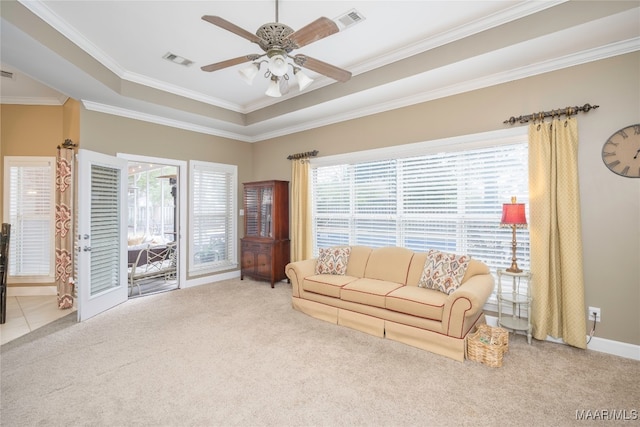 living room with a tray ceiling, light carpet, ceiling fan, and ornamental molding