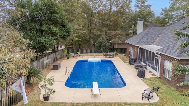 view of swimming pool featuring a sunroom, a diving board, and a patio area