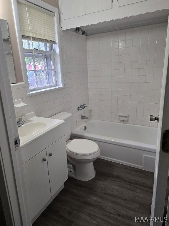 full bathroom with tile walls, hardwood / wood-style floors, vanity, toilet, and tiled shower / bath