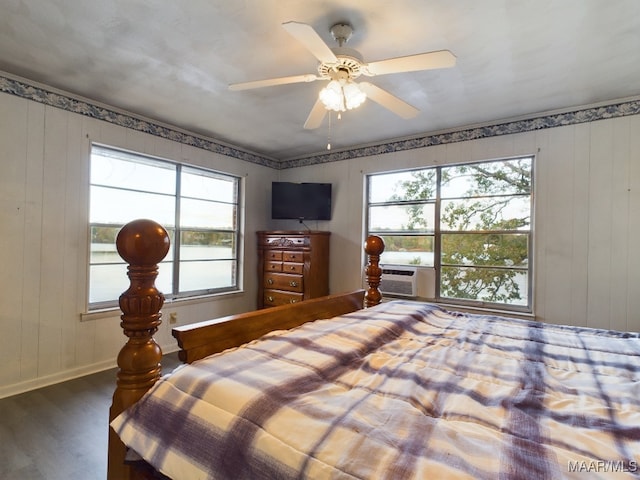 bedroom featuring ceiling fan, wooden walls, and hardwood / wood-style flooring