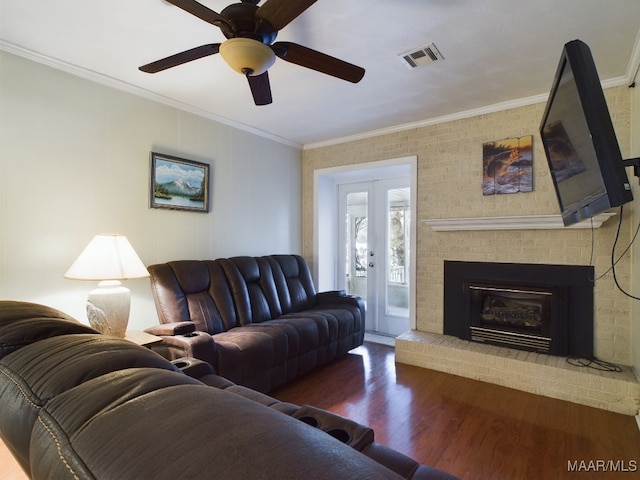 living room featuring french doors, ceiling fan, crown molding, wood-type flooring, and a fireplace