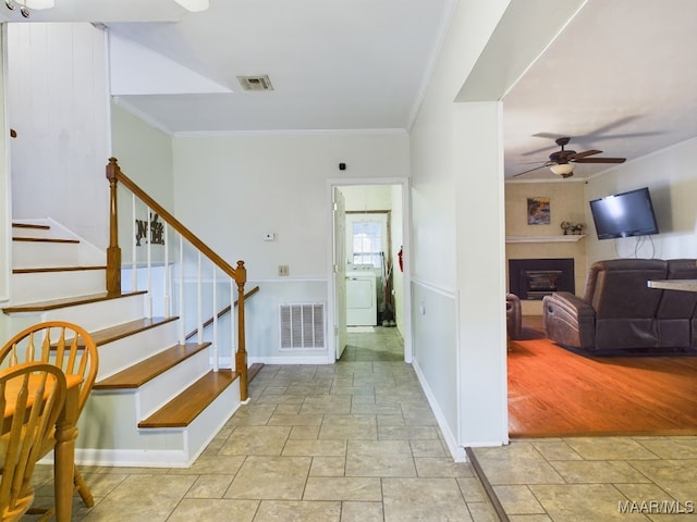 entryway with ceiling fan, washer / dryer, ornamental molding, and light wood-type flooring