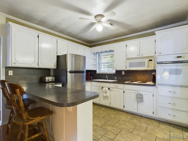 kitchen featuring kitchen peninsula, white appliances, and ornamental molding