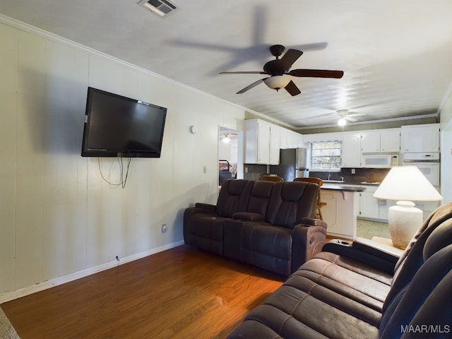 living room with dark hardwood / wood-style floors, ceiling fan, and crown molding