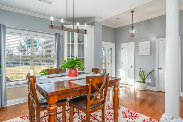 dining space featuring a healthy amount of sunlight, light wood-type flooring, ornamental molding, and decorative columns