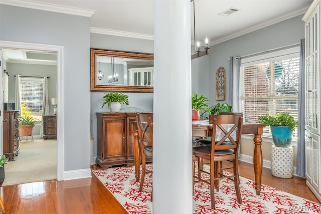 dining space with crown molding, hardwood / wood-style floors, and a notable chandelier