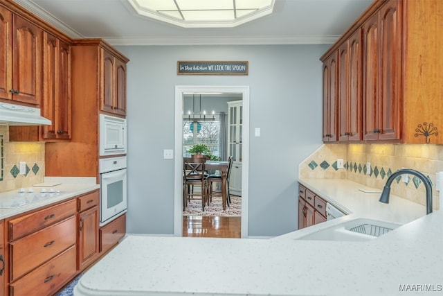 kitchen with backsplash, crown molding, white appliances, and sink