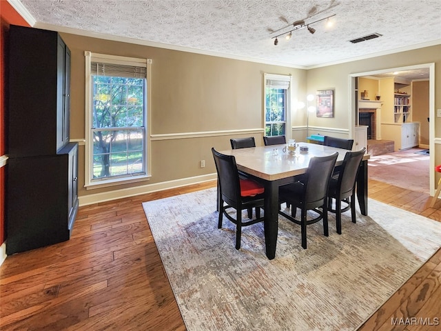 dining room featuring crown molding, a textured ceiling, and dark wood-type flooring