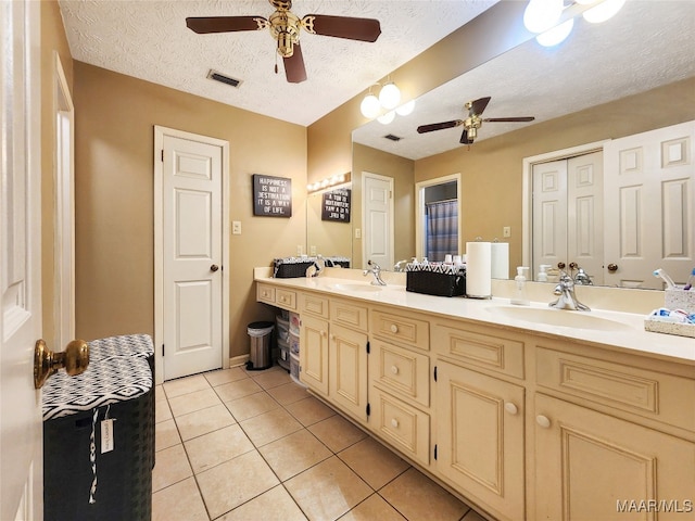 bathroom with tile patterned flooring, vanity, ceiling fan, and a textured ceiling