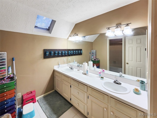 bathroom with vaulted ceiling with skylight, tile patterned flooring, a textured ceiling, and vanity