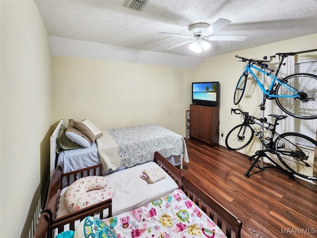 bedroom with ceiling fan, dark hardwood / wood-style flooring, and a textured ceiling