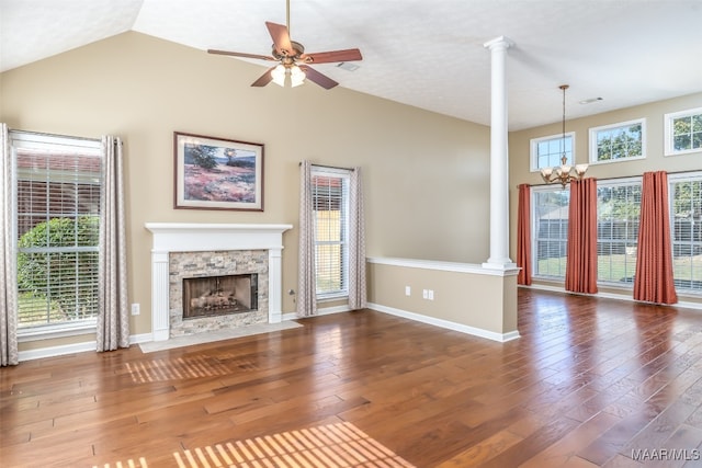 unfurnished living room featuring a stone fireplace, dark wood-type flooring, and decorative columns