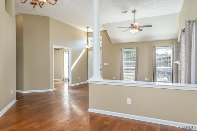 empty room with decorative columns, a textured ceiling, vaulted ceiling, ceiling fan, and dark hardwood / wood-style floors