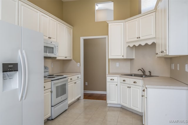 kitchen featuring white cabinets, light tile patterned floors, white appliances, and sink