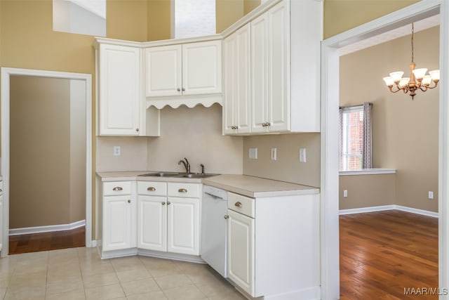 kitchen with light wood-type flooring, white dishwasher, sink, white cabinets, and hanging light fixtures