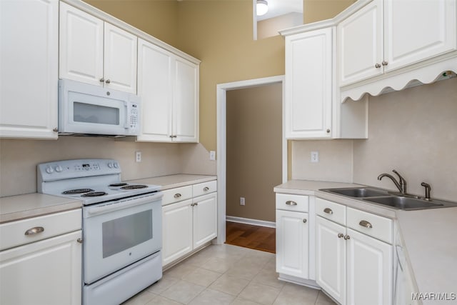 kitchen with light tile patterned floors, white appliances, white cabinetry, and sink