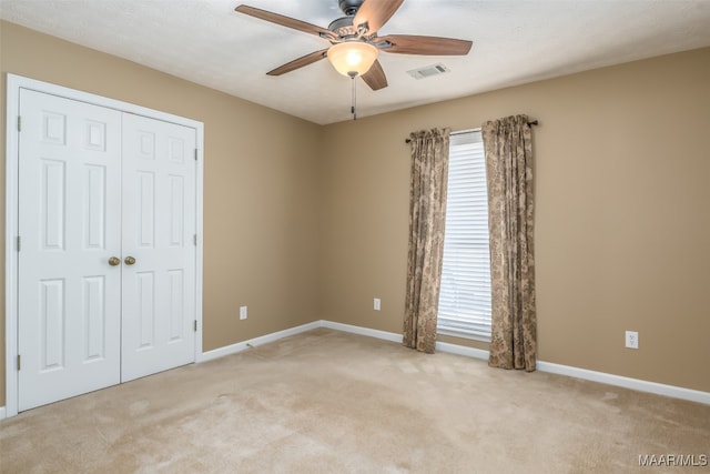 unfurnished bedroom with ceiling fan, light colored carpet, and a closet