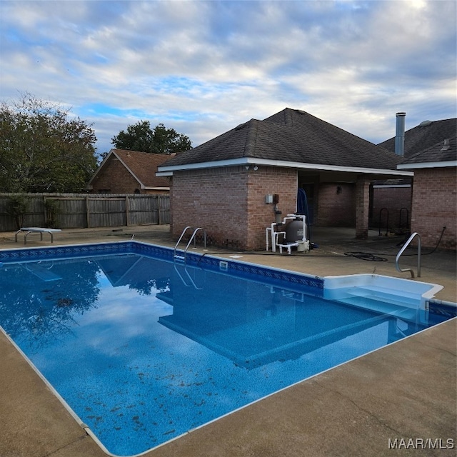 view of swimming pool with a patio area and a diving board