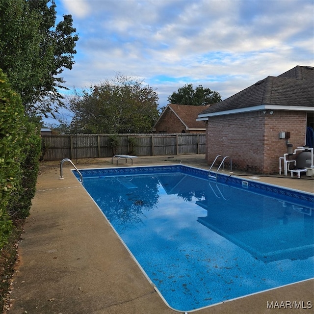 view of pool with a patio and a diving board