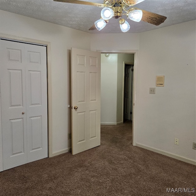 unfurnished bedroom featuring dark colored carpet, ceiling fan, a textured ceiling, and a closet