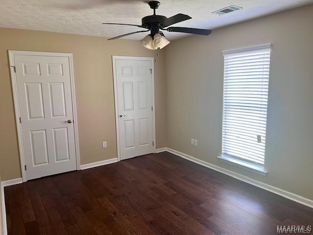 unfurnished bedroom with ceiling fan, dark hardwood / wood-style flooring, and a textured ceiling