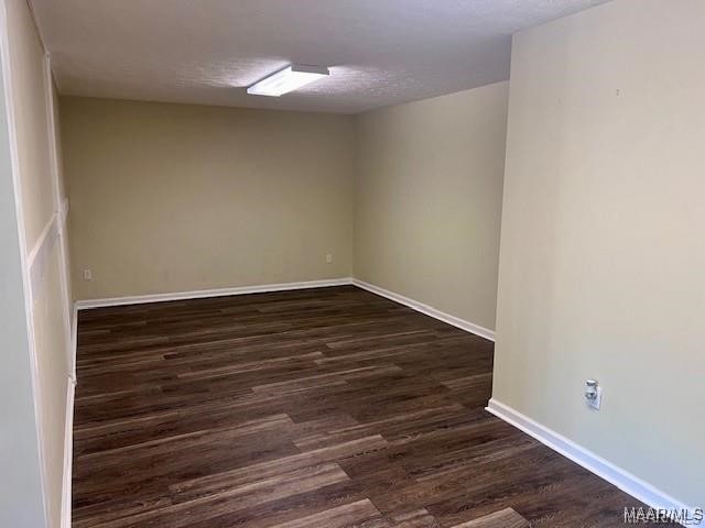 empty room with dark hardwood / wood-style flooring and a textured ceiling