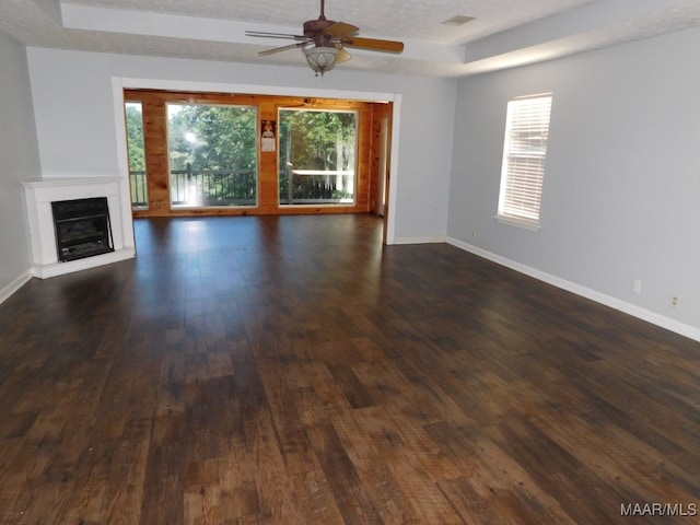 unfurnished living room with a textured ceiling, ceiling fan, and dark wood-type flooring