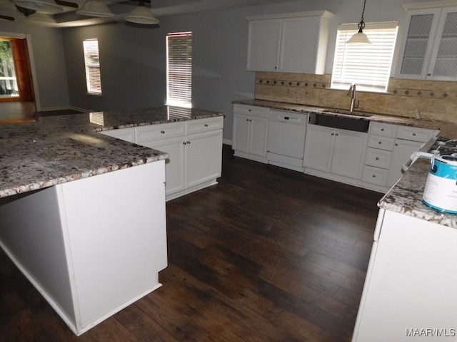 kitchen featuring pendant lighting, dishwasher, sink, dark hardwood / wood-style floors, and white cabinetry