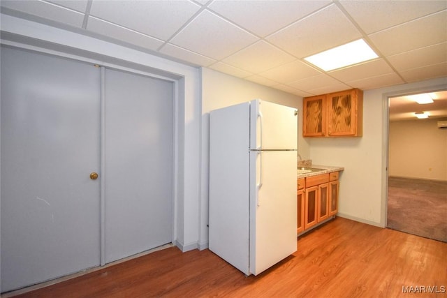 171 Griffith Ln, Tallassee, AL 36078 - kitchen with freestanding refrigerator, brown cabinets, light wood-style flooring, a paneled ceiling, and light countertops