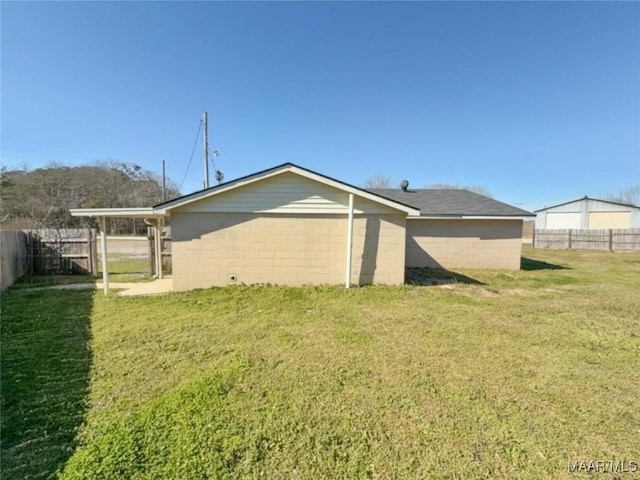 rear view of property with a yard, concrete block siding, and fence