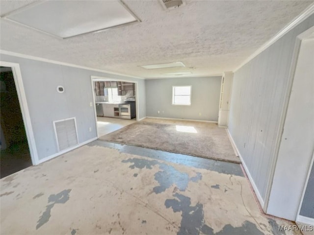 empty room with a textured ceiling, baseboards, visible vents, and crown molding