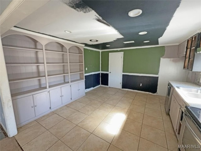 empty room featuring crown molding, light tile patterned flooring, a sink, and built in features