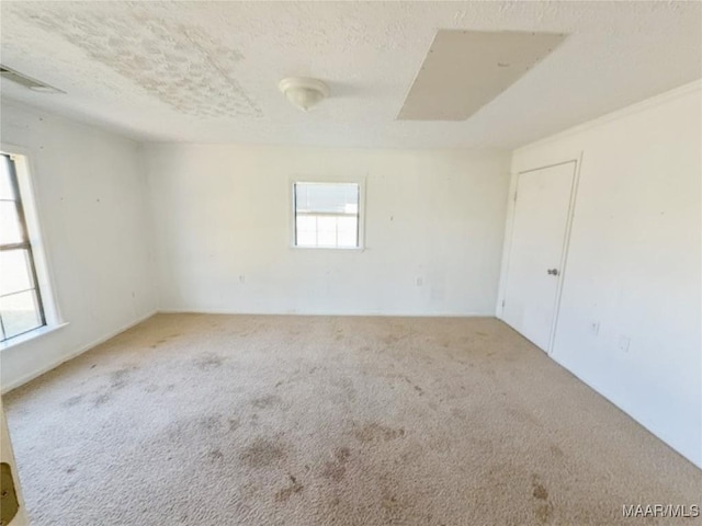 carpeted empty room featuring a textured ceiling