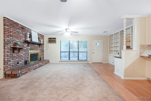 unfurnished living room featuring ceiling fan, a brick fireplace, built in features, a wall unit AC, and light hardwood / wood-style floors