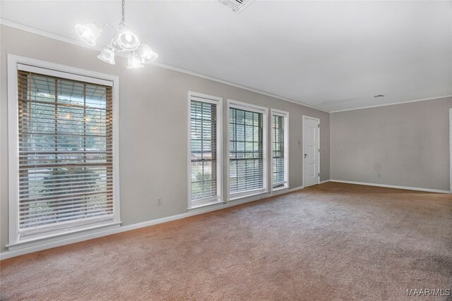 carpeted spare room with ornamental molding and a notable chandelier