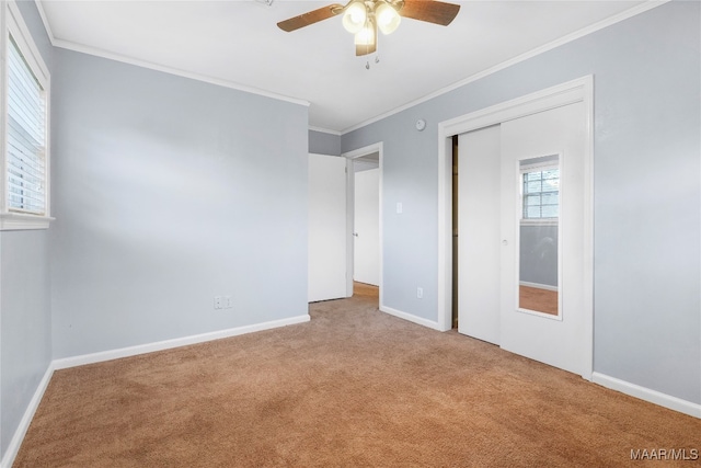 unfurnished bedroom with a closet, light colored carpet, ceiling fan, and crown molding