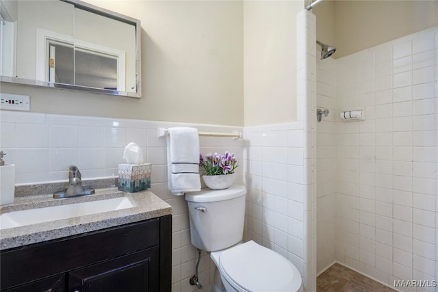 bathroom with tiled shower, vanity, tile walls, and toilet