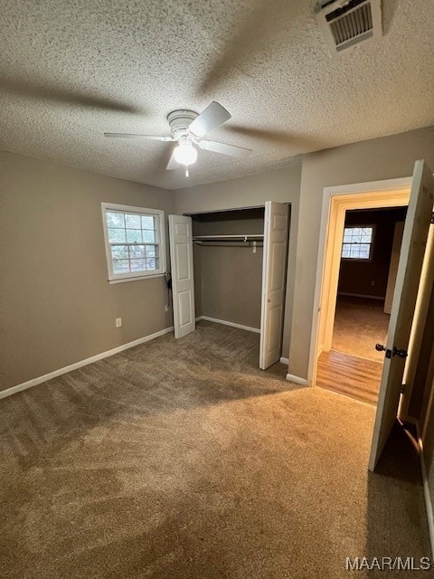 unfurnished bedroom featuring multiple windows, a textured ceiling, a closet, and ceiling fan