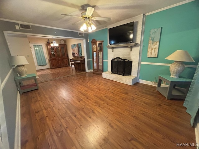 living room with a brick fireplace, crown molding, hardwood / wood-style floors, and ceiling fan