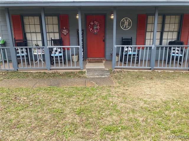 view of exterior entry featuring a yard and covered porch