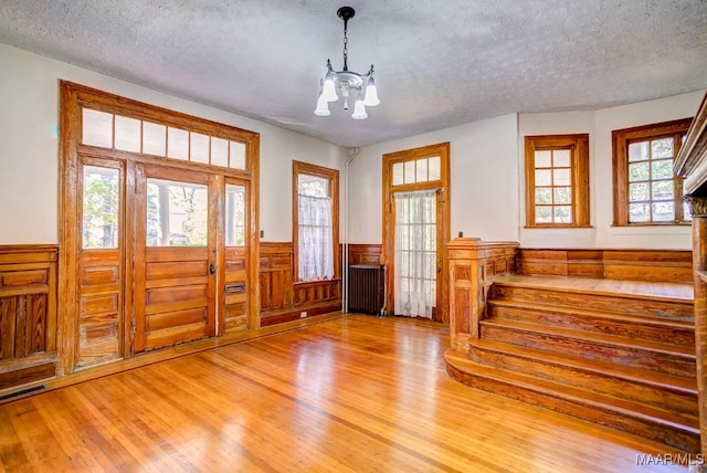 entryway featuring wood-type flooring, a textured ceiling, radiator, and an inviting chandelier