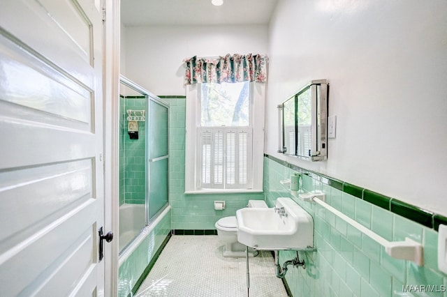 full bathroom featuring tile patterned floors, sink, toilet, enclosed tub / shower combo, and tile walls