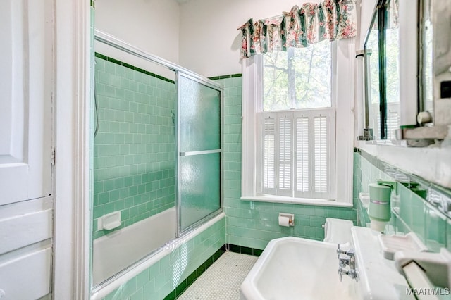 bathroom featuring shower / bath combination with glass door, tile patterned floors, tile walls, and sink